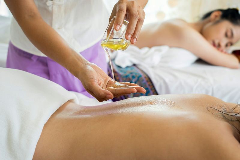 Oliemassage — warme olie wordt op de rug aangebracht